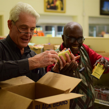 Volunteers put cans of black bean on shelf at bishops storehouse